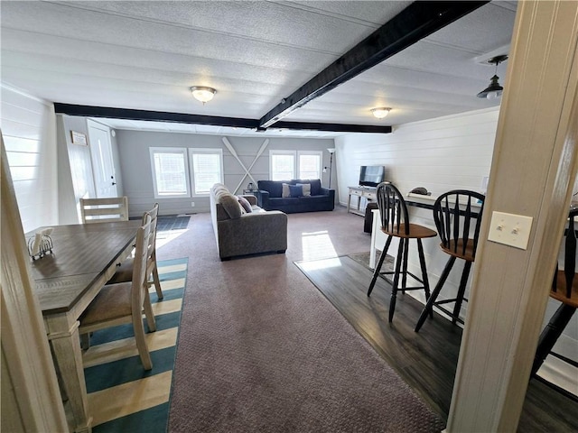 living area featuring beamed ceiling and wood finished floors