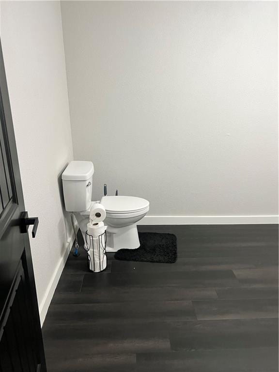 bathroom with toilet, baseboards, and wood finished floors