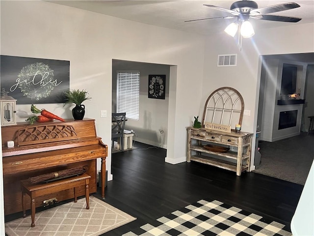 living area with visible vents, ceiling fan, baseboards, and wood finished floors