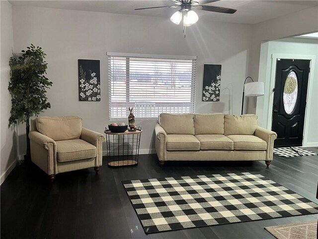 living area featuring a ceiling fan, baseboards, and dark wood-style flooring