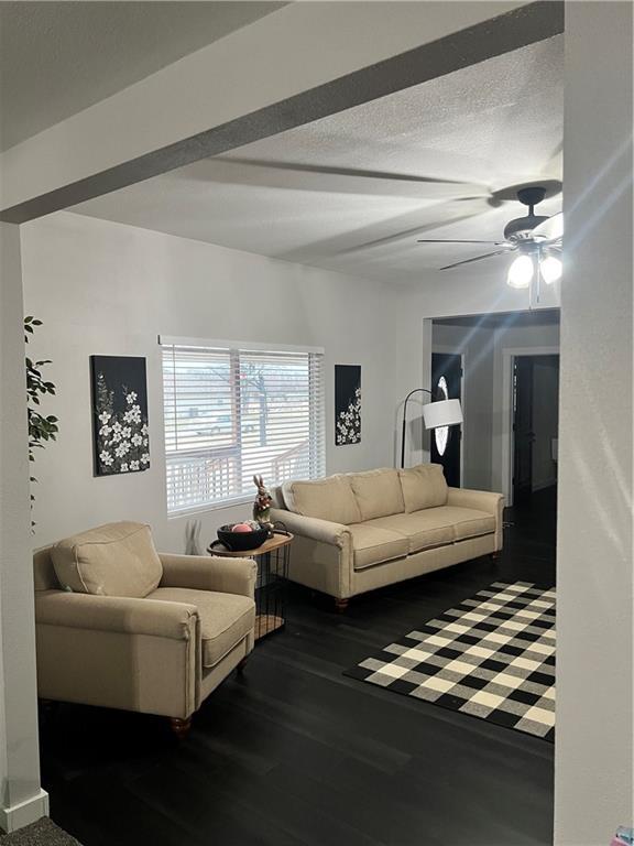 living room featuring a textured ceiling, wood finished floors, and a ceiling fan