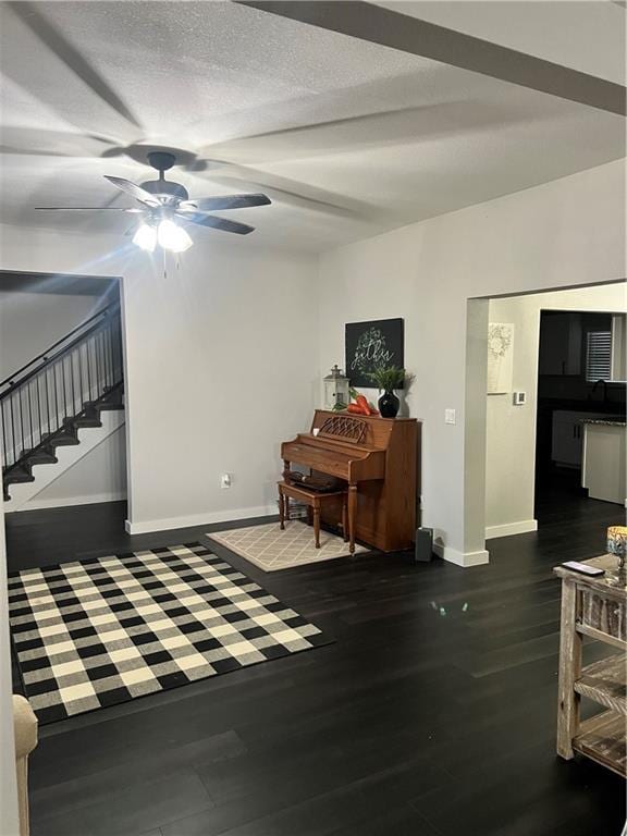 interior space with a ceiling fan, a textured ceiling, baseboards, and wood finished floors