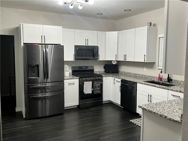 kitchen with light stone counters, dark wood finished floors, a sink, and black appliances