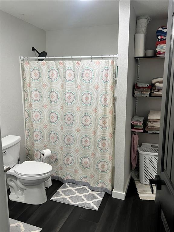 bathroom featuring a shower with curtain, toilet, and wood finished floors