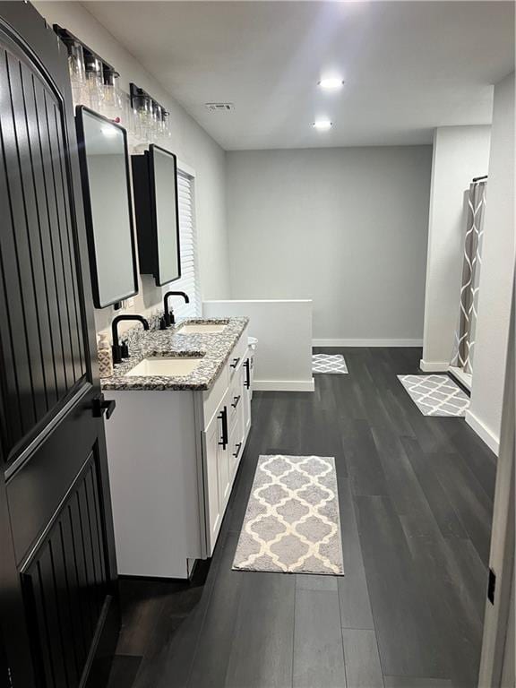 bathroom with double vanity, a sink, baseboards, and wood finished floors