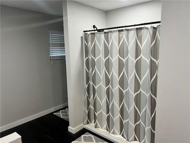 full bath featuring a shower with curtain, baseboards, and wood finished floors