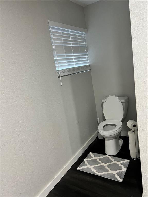 bathroom featuring toilet, baseboards, and wood finished floors