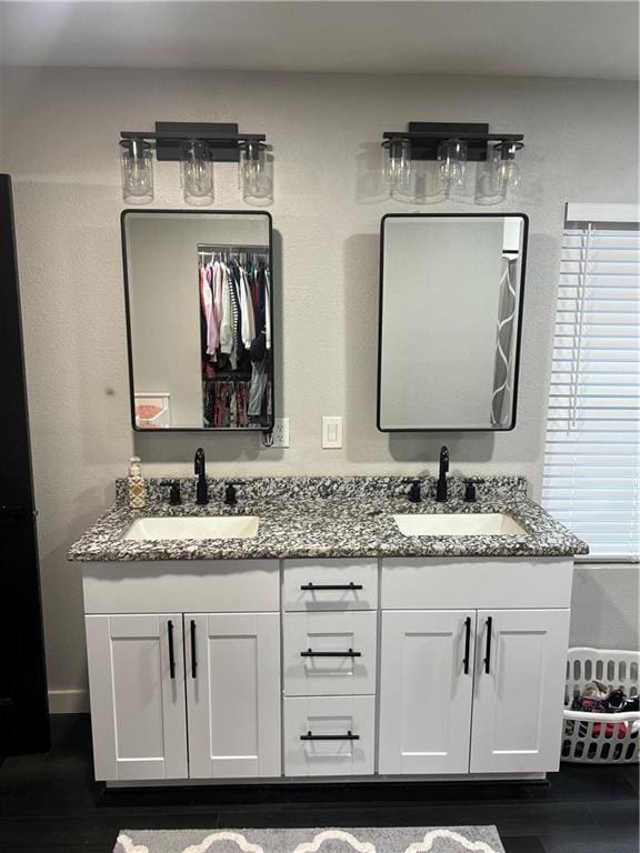 full bath with a walk in closet, wood finished floors, a sink, and double vanity