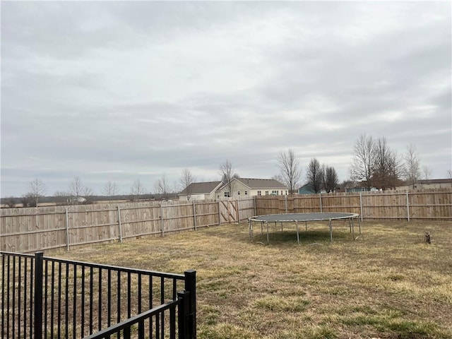 view of yard featuring a trampoline and a fenced backyard