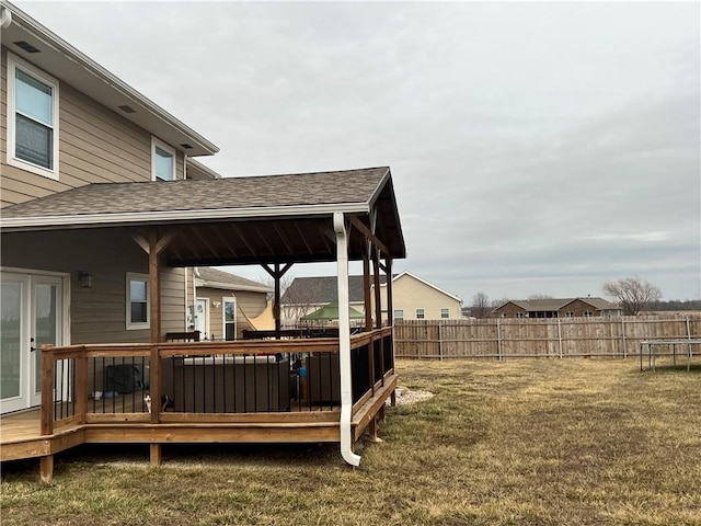 view of yard with a trampoline, fence, and a deck