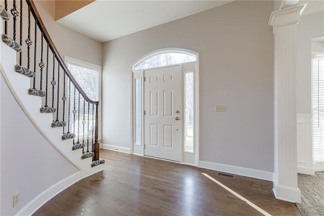 foyer entrance with visible vents, wood finished floors, stairway, baseboards, and ornate columns