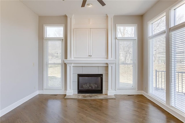 unfurnished living room featuring baseboards, a healthy amount of sunlight, wood finished floors, and a fireplace