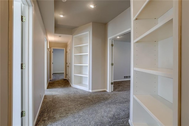 corridor with carpet, visible vents, and baseboards