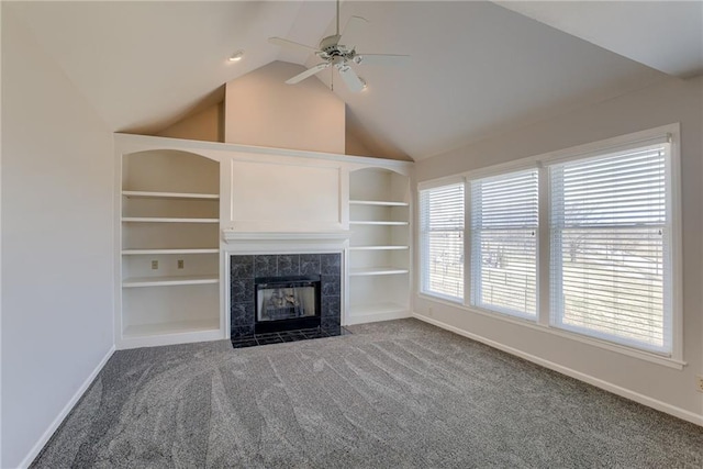 unfurnished living room featuring built in features, baseboards, lofted ceiling, a tile fireplace, and carpet flooring