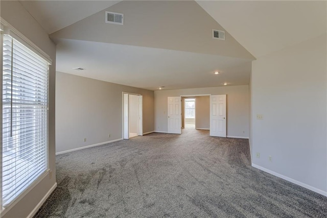 carpeted spare room featuring visible vents, baseboards, and high vaulted ceiling