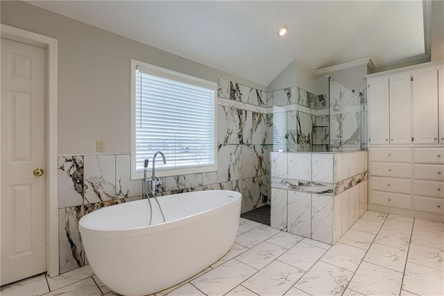 bathroom with a marble finish shower, lofted ceiling, a freestanding tub, tile walls, and marble finish floor