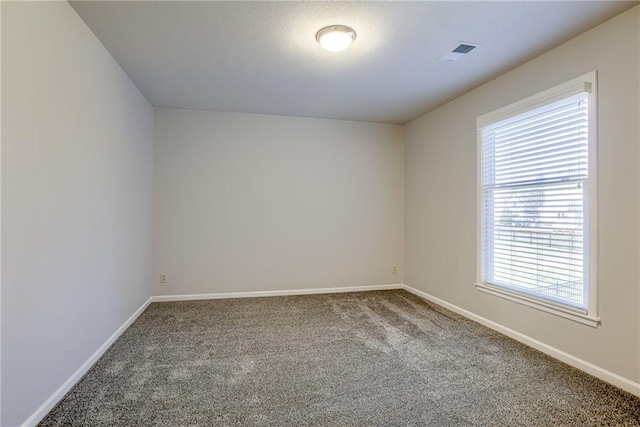 unfurnished room with visible vents, baseboards, and carpet