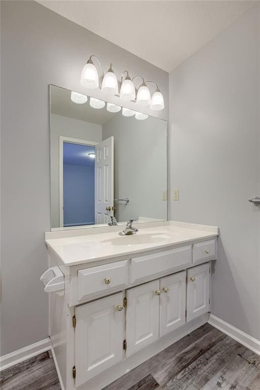 bathroom with baseboards, wood finished floors, and vanity