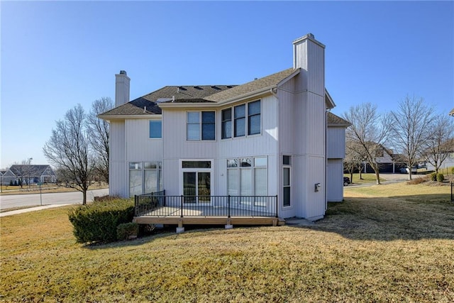 back of property with a wooden deck, a lawn, and a chimney