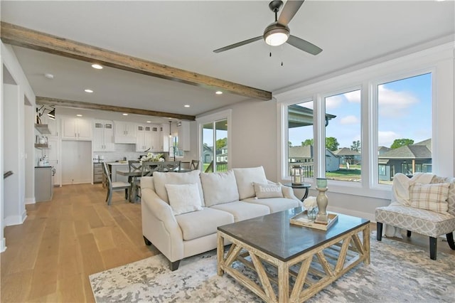 living area featuring recessed lighting, a ceiling fan, baseboards, light wood-type flooring, and beamed ceiling