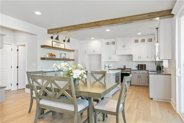 dining room with light wood finished floors, beam ceiling, and recessed lighting