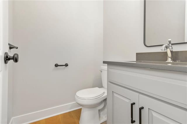 bathroom featuring baseboards, vanity, toilet, and wood finished floors