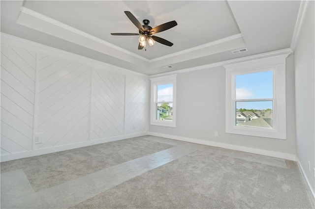 carpeted spare room featuring visible vents, a tray ceiling, baseboards, and ornamental molding