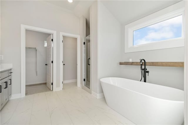 full bath featuring baseboards, marble finish floor, vanity, a freestanding tub, and a shower stall