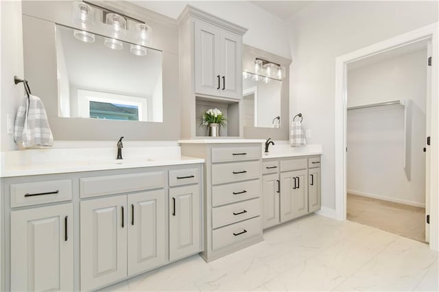 bathroom with marble finish floor, vanity, baseboards, and a spacious closet