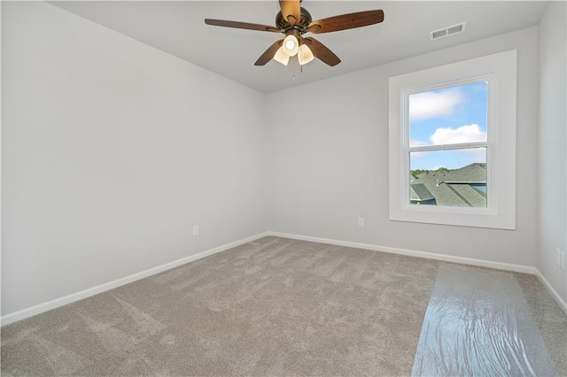 carpeted spare room with visible vents, baseboards, and ceiling fan