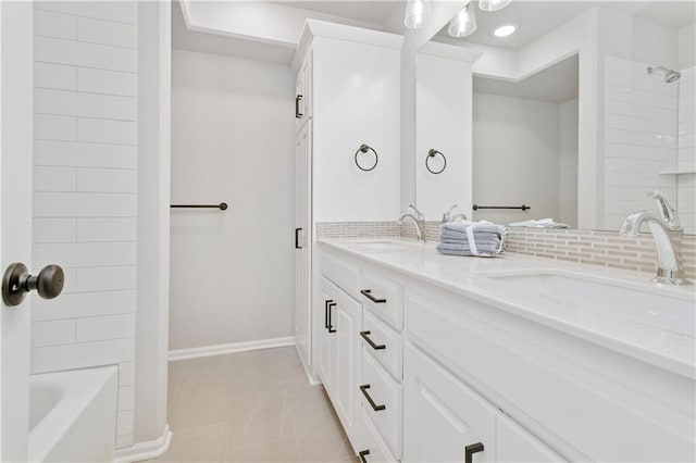 full bath with baseboards, double vanity, a sink, and tile patterned floors