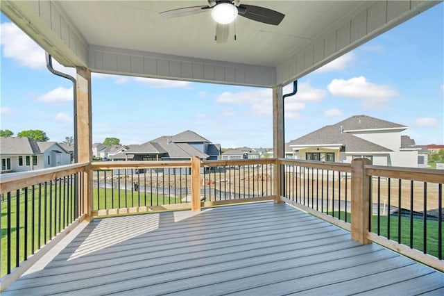 wooden deck with a residential view, a lawn, and a ceiling fan