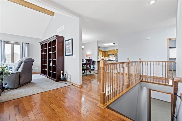 interior space featuring visible vents, an upstairs landing, wood-type flooring, baseboards, and vaulted ceiling