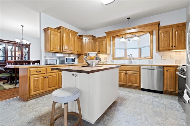 kitchen with a breakfast bar, a sink, wood counters, appliances with stainless steel finishes, and a chandelier