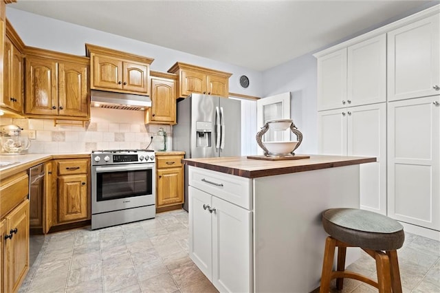 kitchen with tasteful backsplash, a kitchen island, under cabinet range hood, stainless steel appliances, and wood counters