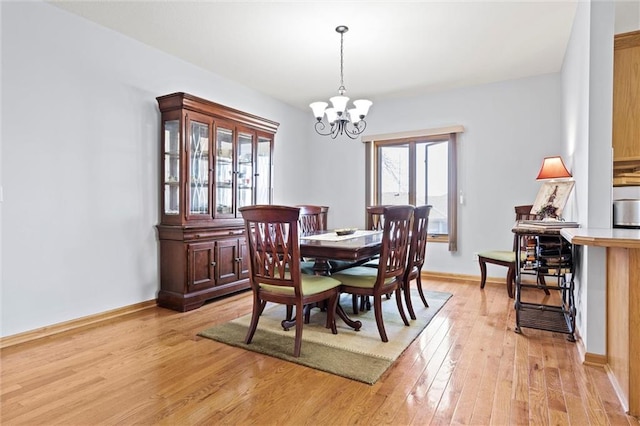 dining space featuring light wood-type flooring, baseboards, and a notable chandelier