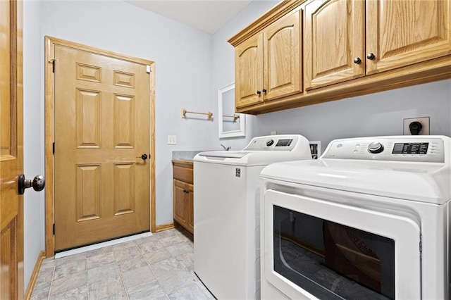 washroom with baseboards, cabinet space, and washing machine and dryer