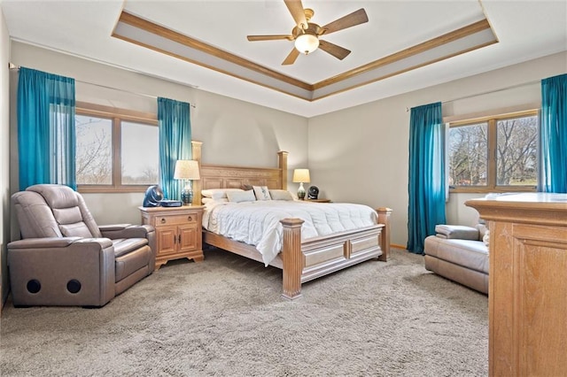 carpeted bedroom featuring a raised ceiling, a ceiling fan, and ornamental molding