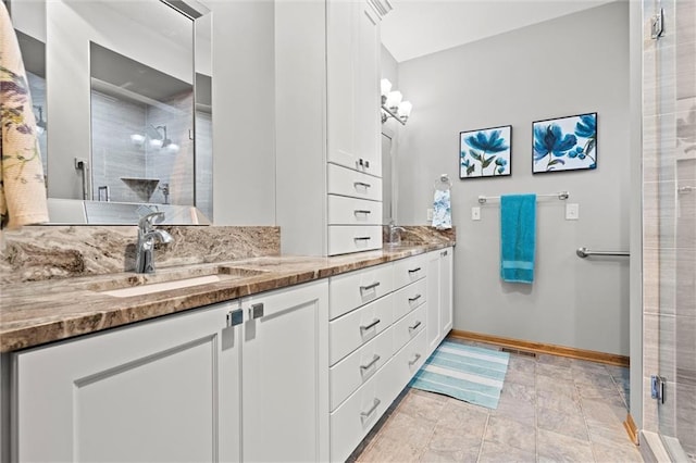 full bath with a shower stall, double vanity, baseboards, and a sink