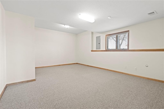 carpeted empty room with electric panel, baseboards, visible vents, and a textured ceiling