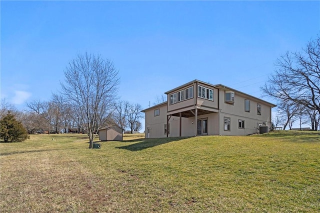 rear view of property featuring a yard, an outbuilding, central AC unit, and a shed