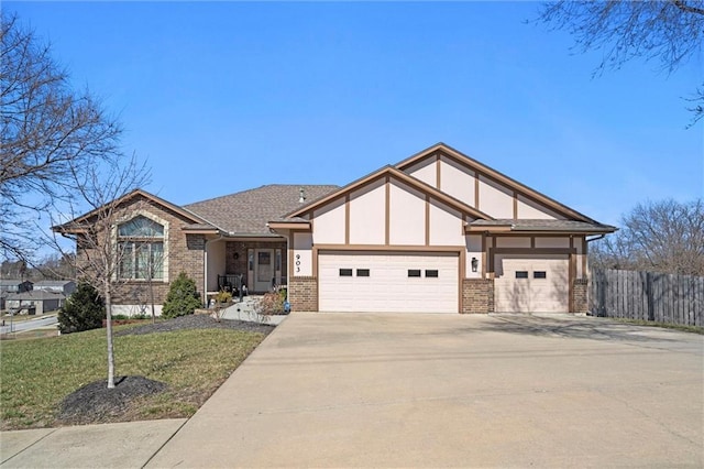 view of front of property with brick siding, a front lawn, fence, driveway, and an attached garage