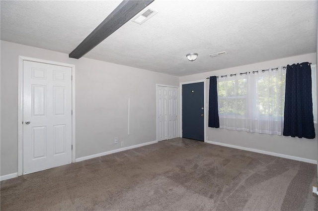 carpeted empty room featuring baseboards, beam ceiling, visible vents, and a textured ceiling