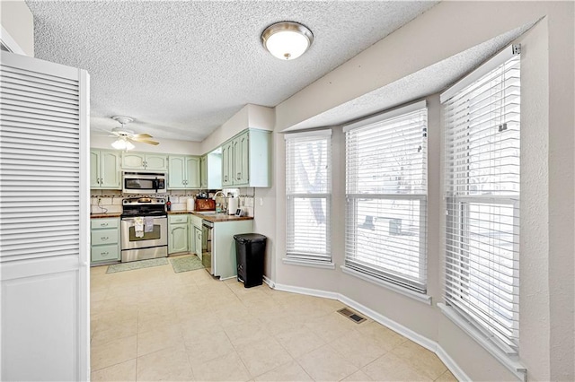 kitchen featuring baseboards, visible vents, stainless steel appliances, green cabinets, and a sink