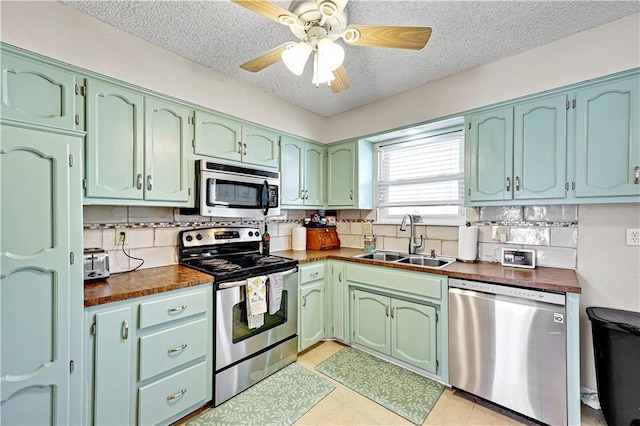 kitchen featuring dark countertops, appliances with stainless steel finishes, green cabinetry, and a sink