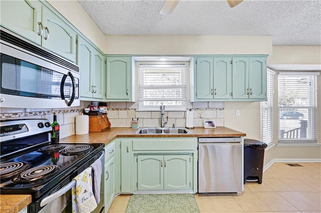 kitchen featuring appliances with stainless steel finishes, plenty of natural light, a sink, and a ceiling fan