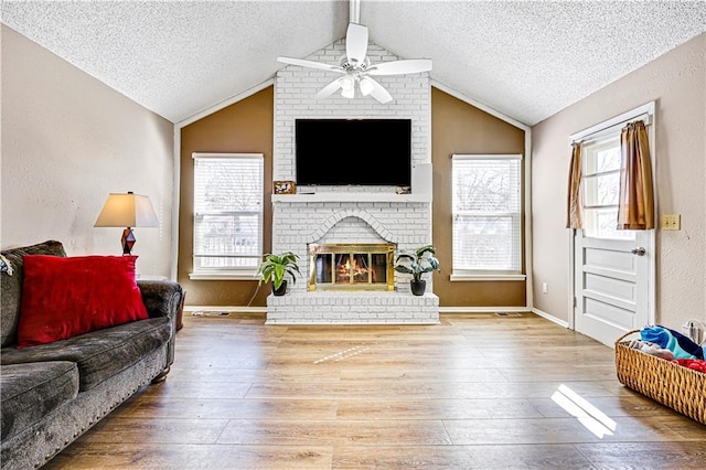 living area with vaulted ceiling with beams, hardwood / wood-style floors, a textured ceiling, and a fireplace