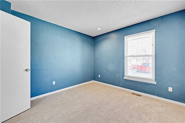 spare room with carpet, baseboards, a textured ceiling, and a textured wall