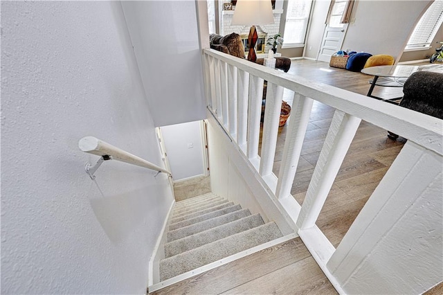 staircase with a textured wall, baseboards, and wood finished floors