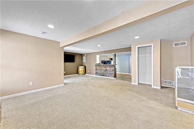 basement with carpet, visible vents, and baseboards